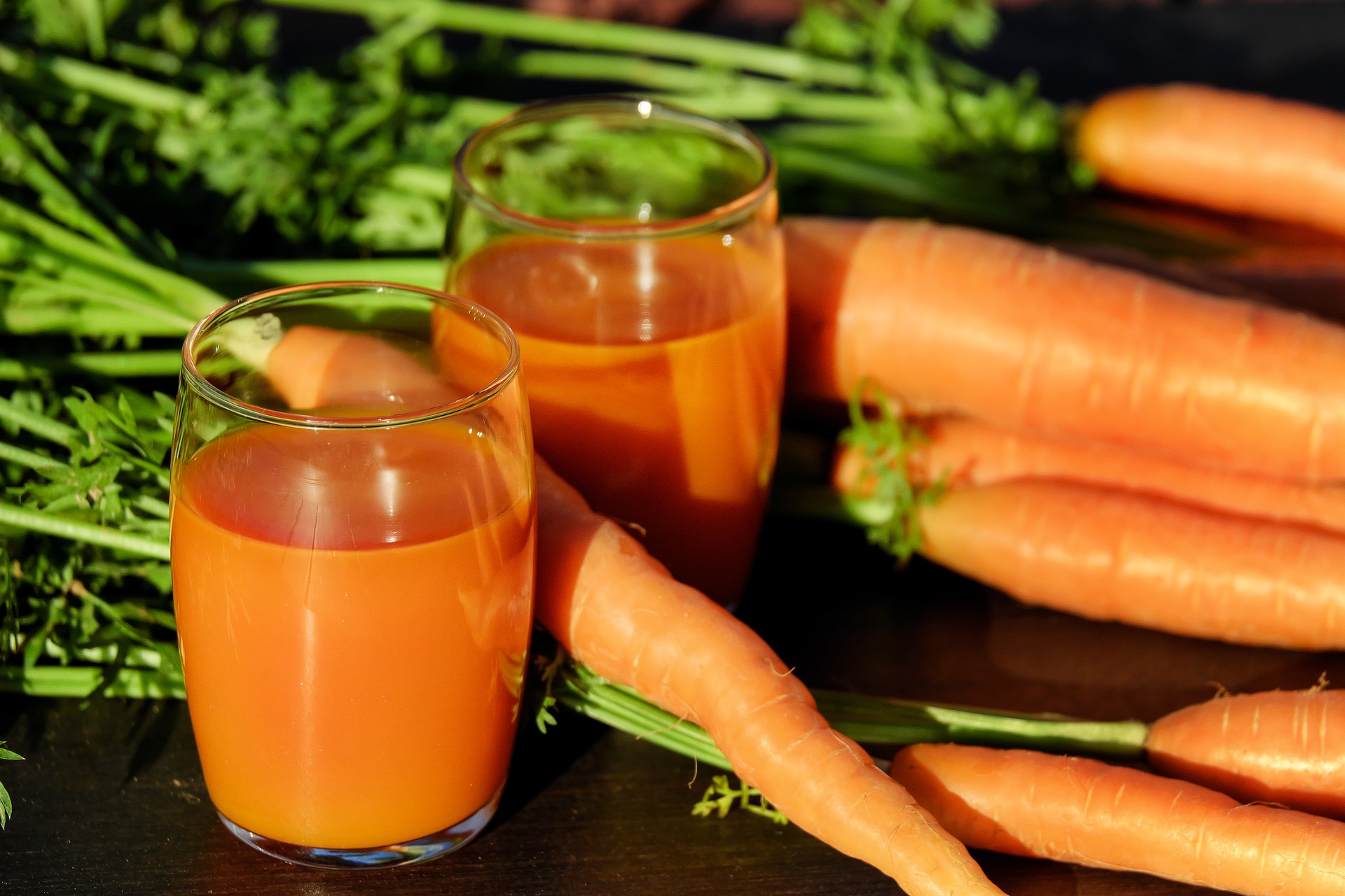 verres remplis de jus de carotte et des carottes posées à côté