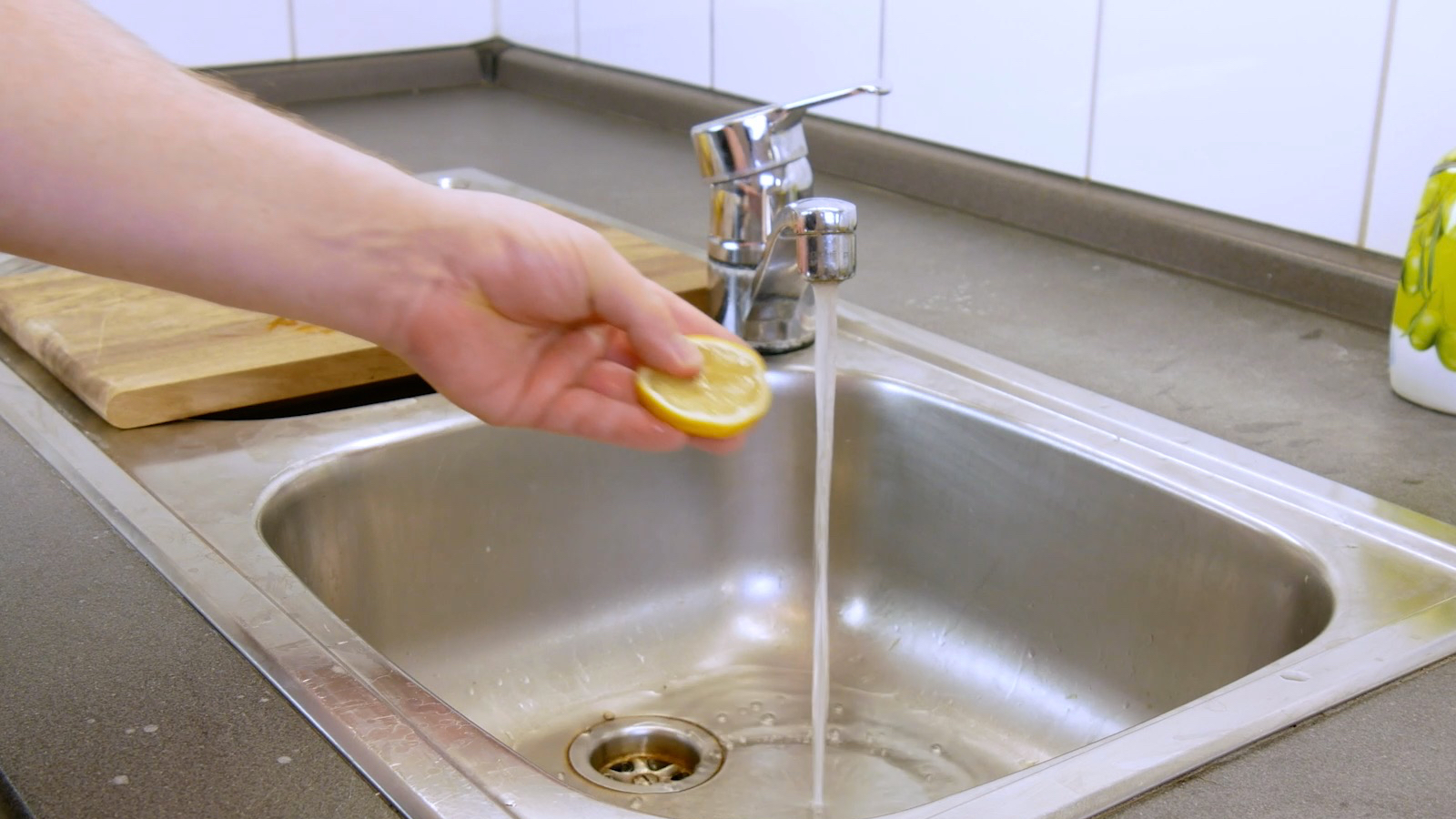 rondelle de citron tenue dans une main qui va passer sous l'eau d'un robinet donc pour se laver les mains
