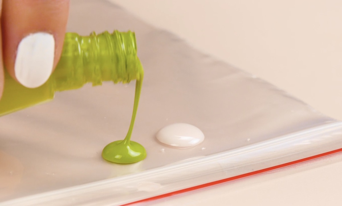 verser du vernis à ongles blanc et vert sur un sachet plastique
