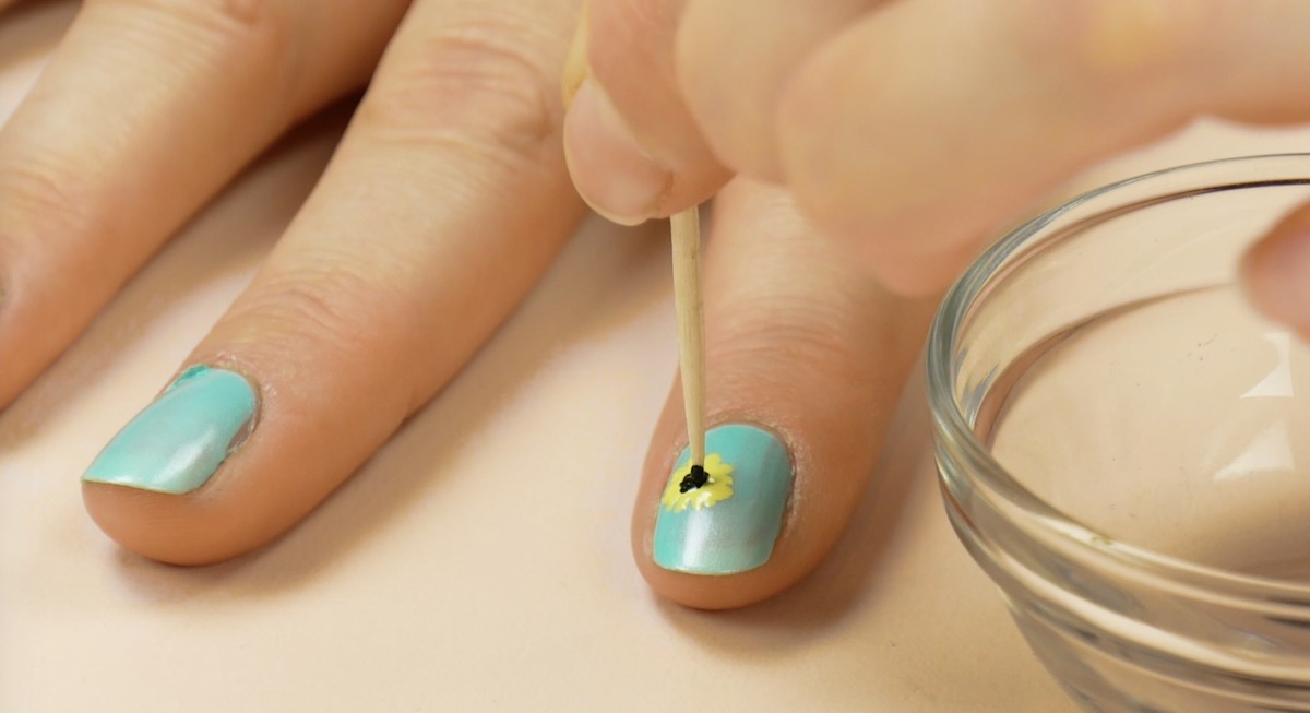 vernis à ongles noir appliqué sur le vernis à ongles jaune à l'aide d'un cure-dents